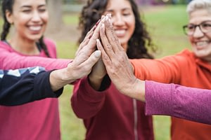 Group of women stacking hands outdoor at city park
